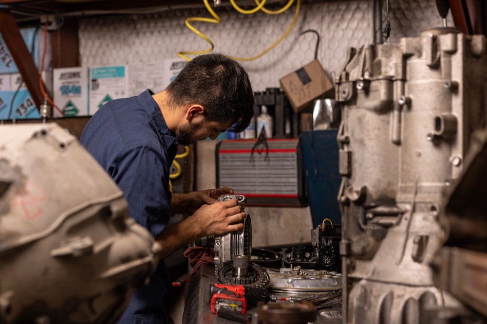 Automotive technician rebuilding a transmission, photographed on location